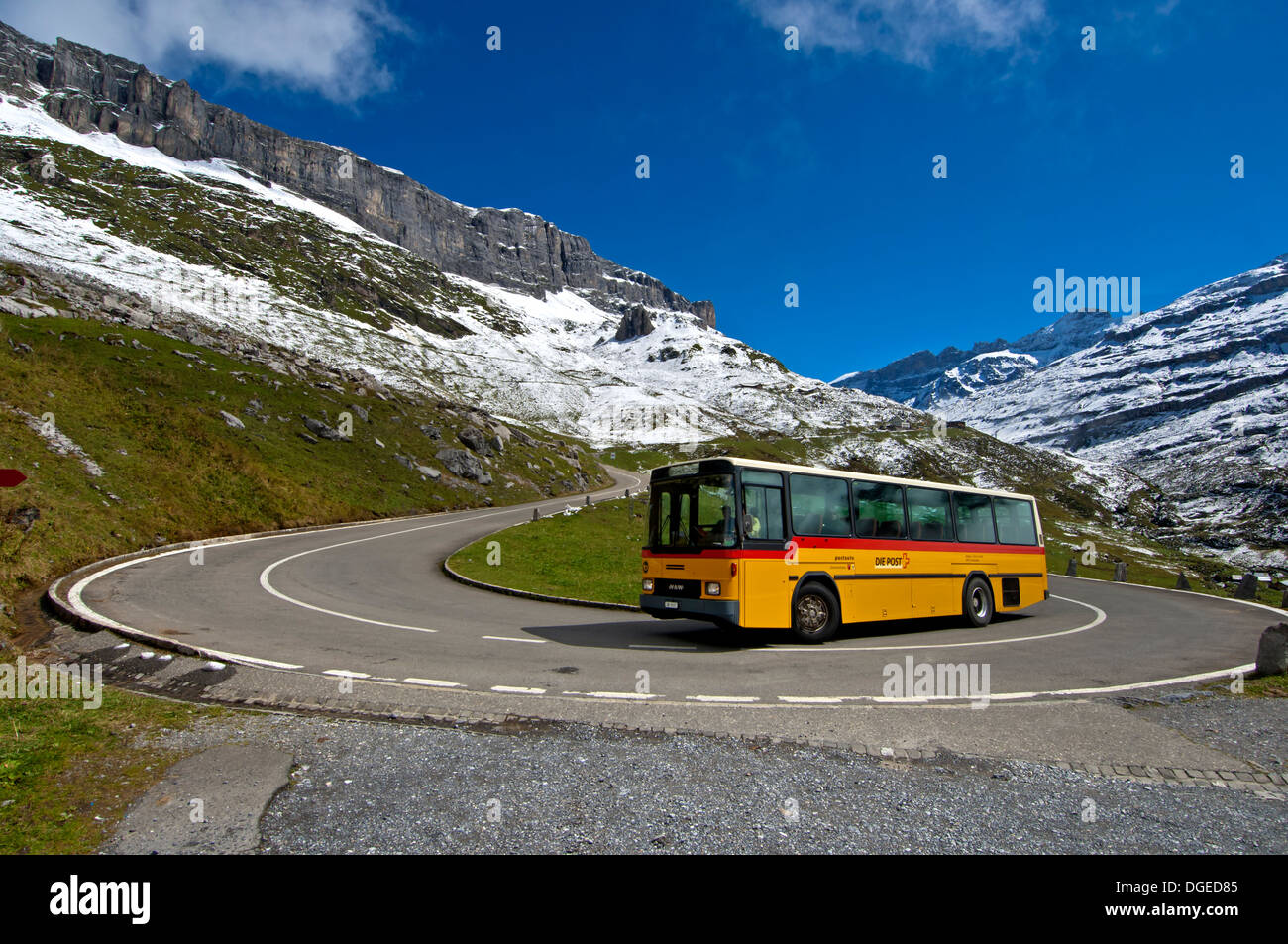 Yellow Swiss Post bus in a hairpin bend on the mountain road to the pass Klausenpass, Canton of Uri, Switzerland Stock Photo