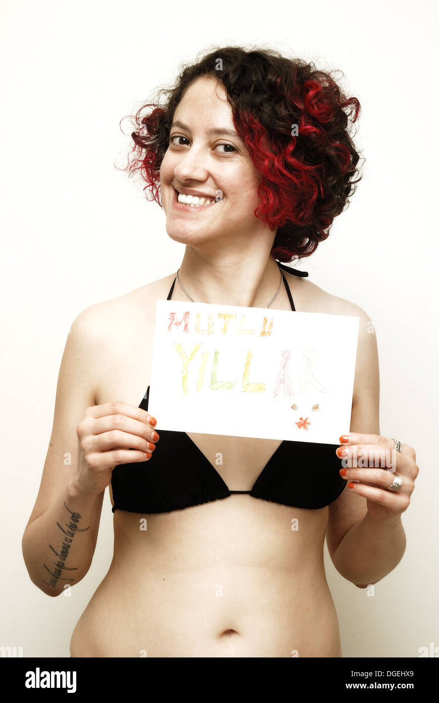 Young woman in bikini holding a 'Mutlu Yıllar' ('Happy New Year' in Turkish) card Stock Photo