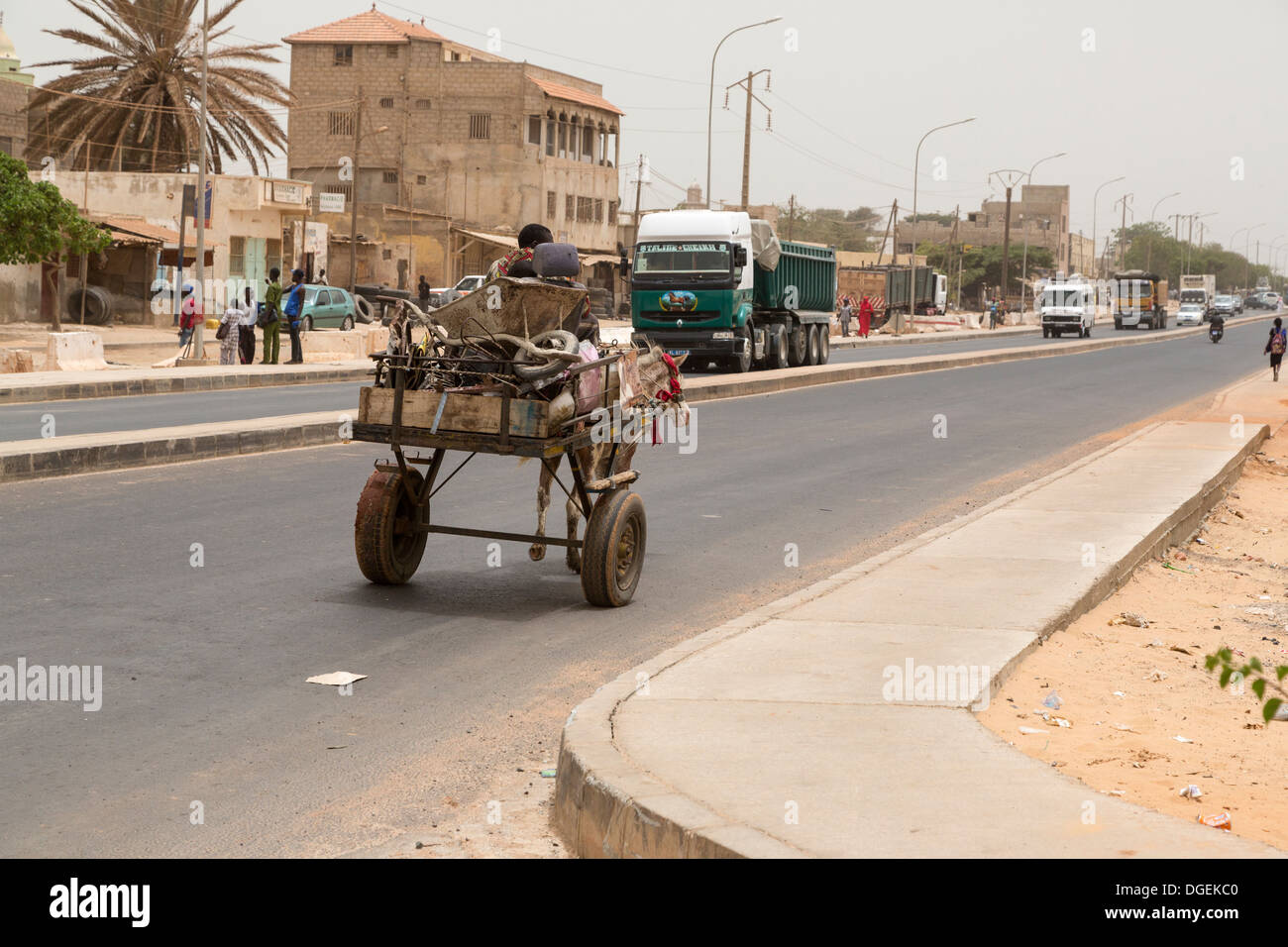 Senegal. A horse-drawn cart shares the divided highway with large trucks on the outskirts of Dakar. Stock Photo