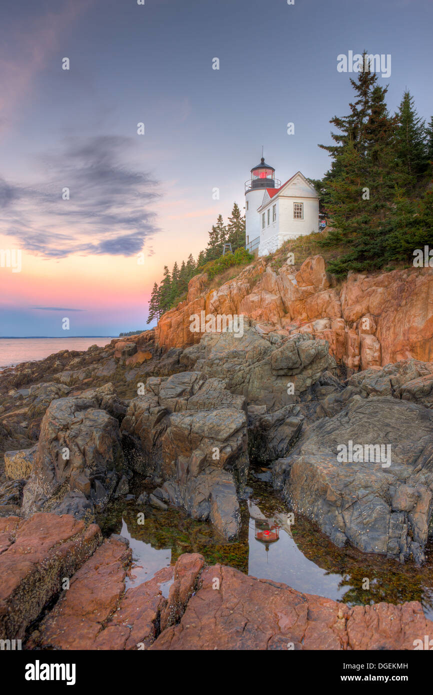 Bass Harbor Head Lighthouse is reflected in a tidal pool shortly before sunrise as it overlooks the entrance to Bass Harbor in Acadia National Park. Stock Photo