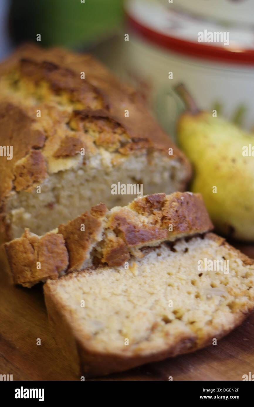 Home made pear and ginger loaf, with ripe pear and cake tins in shallow
