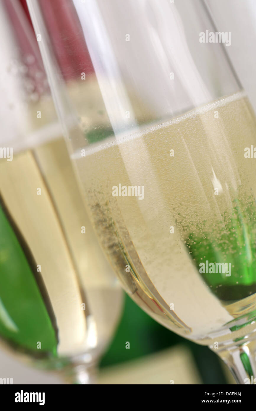 Champagne or sparkling wine with bubbles in a glass with a bottle in the background Stock Photo