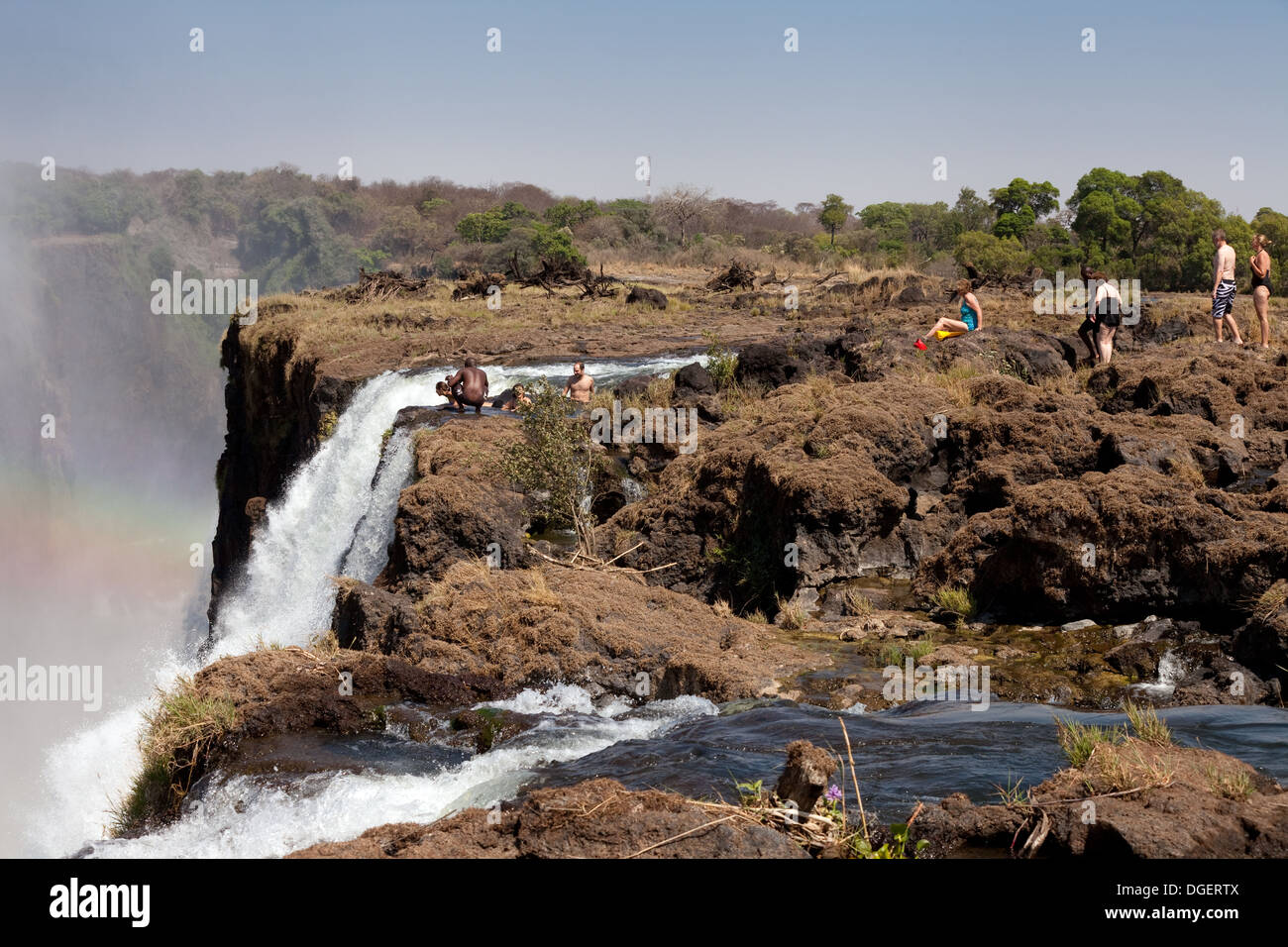 Tourists swimming in Devils Pool at the edge of the Victoria Falls, taken from Livingstone Island, Victoria Falls, Zambia Africa Stock Photo