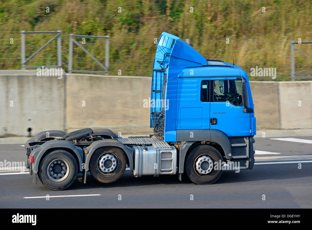 HGV orry tractor unit & driver without trailer and with raised economy axle tyre saver feature activated driving along English UK motorway road Stock Photo