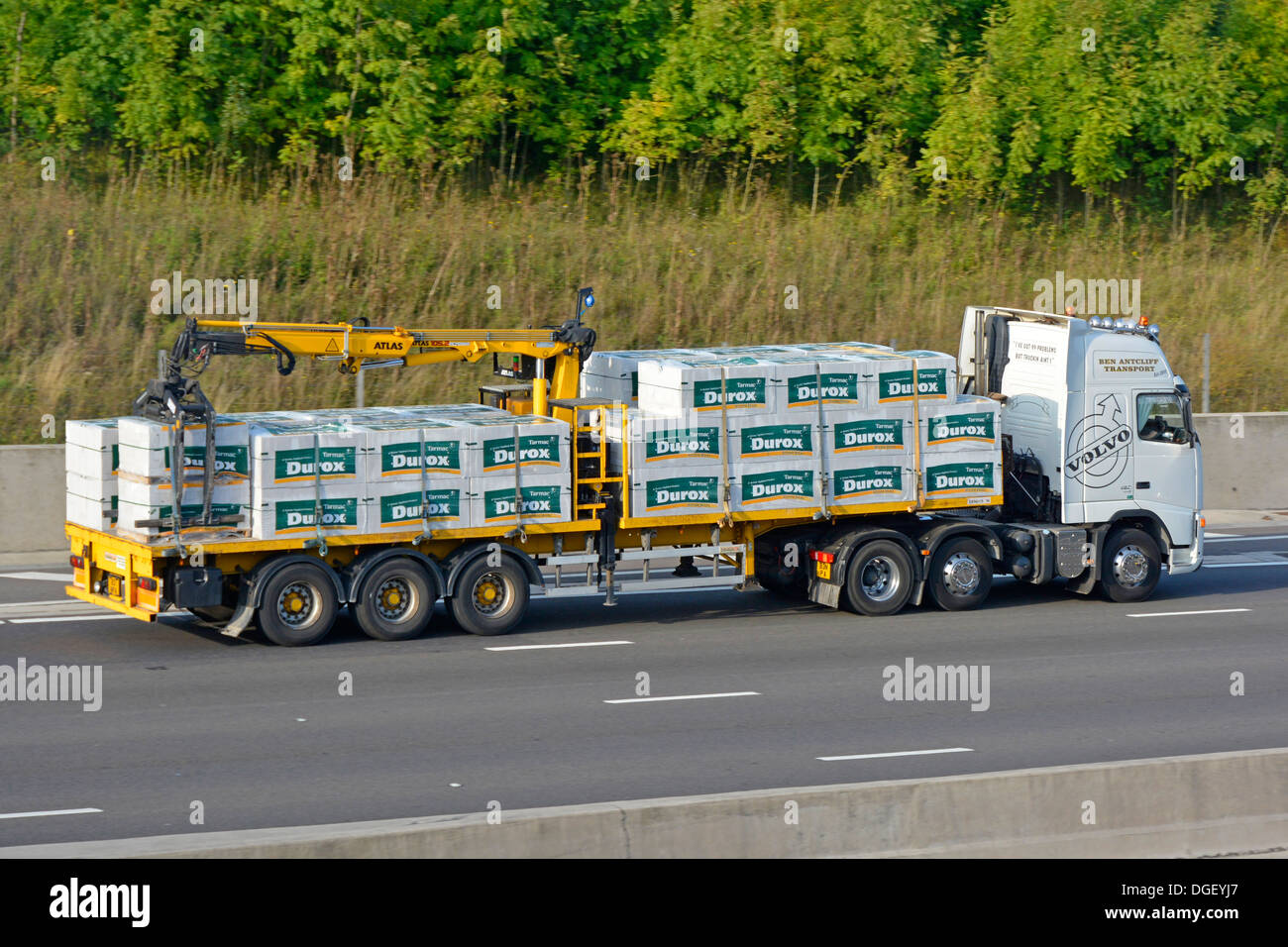 Volvo truck with Atlas crane offload articulated trailer loaded with Durox building blocks for the construction industry Stock Photo