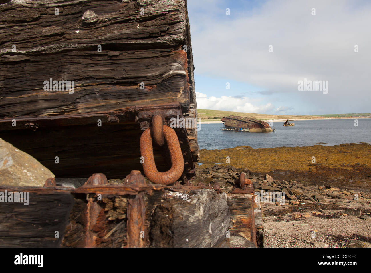 Islands of Orkney, Scotland. Debris on the shore adjacent to Churchill Barrier Number 3 with a blockship in the background. Stock Photo