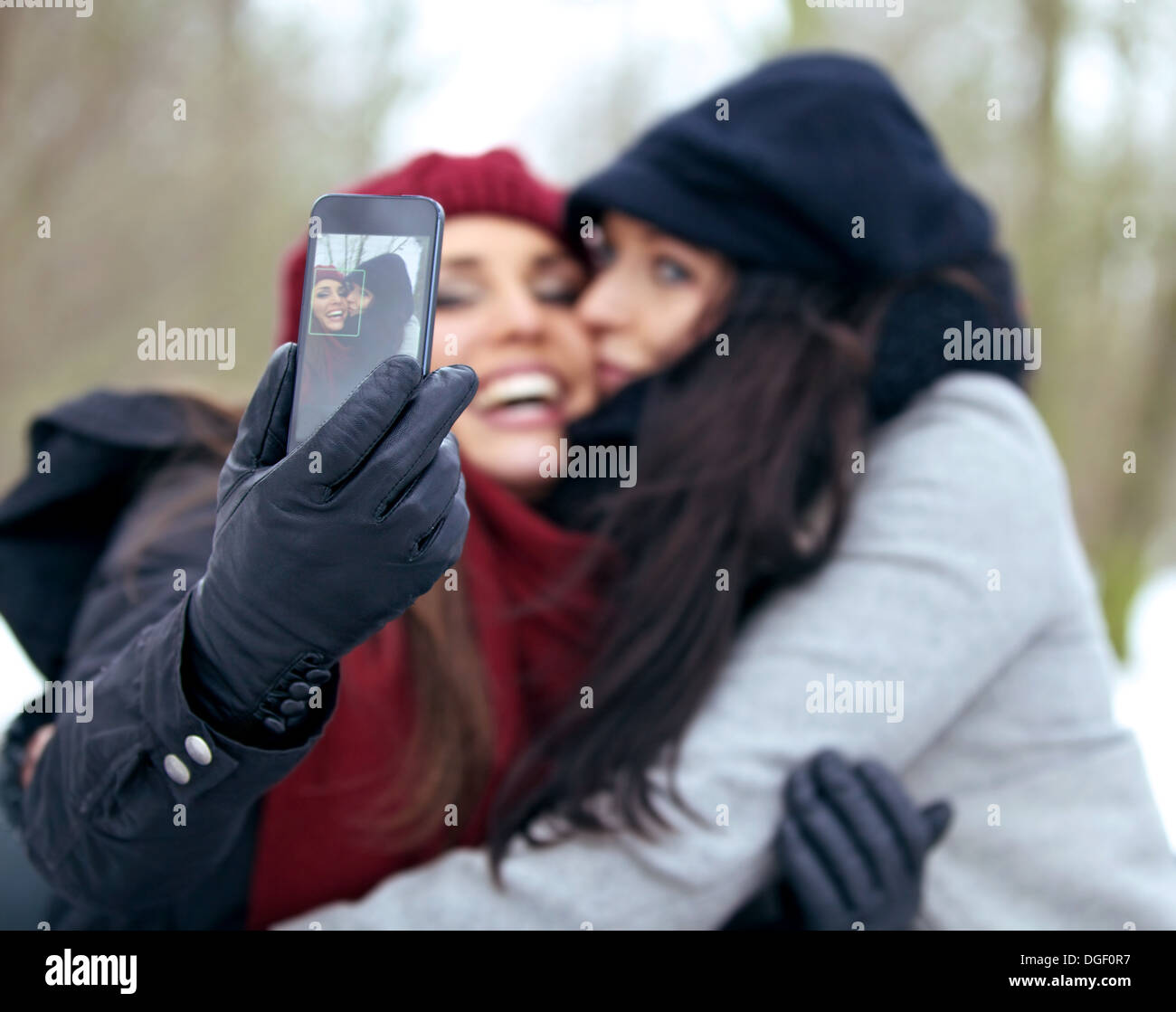 Two fun women looking happy while taking pictures using a smart phone Stock Photo