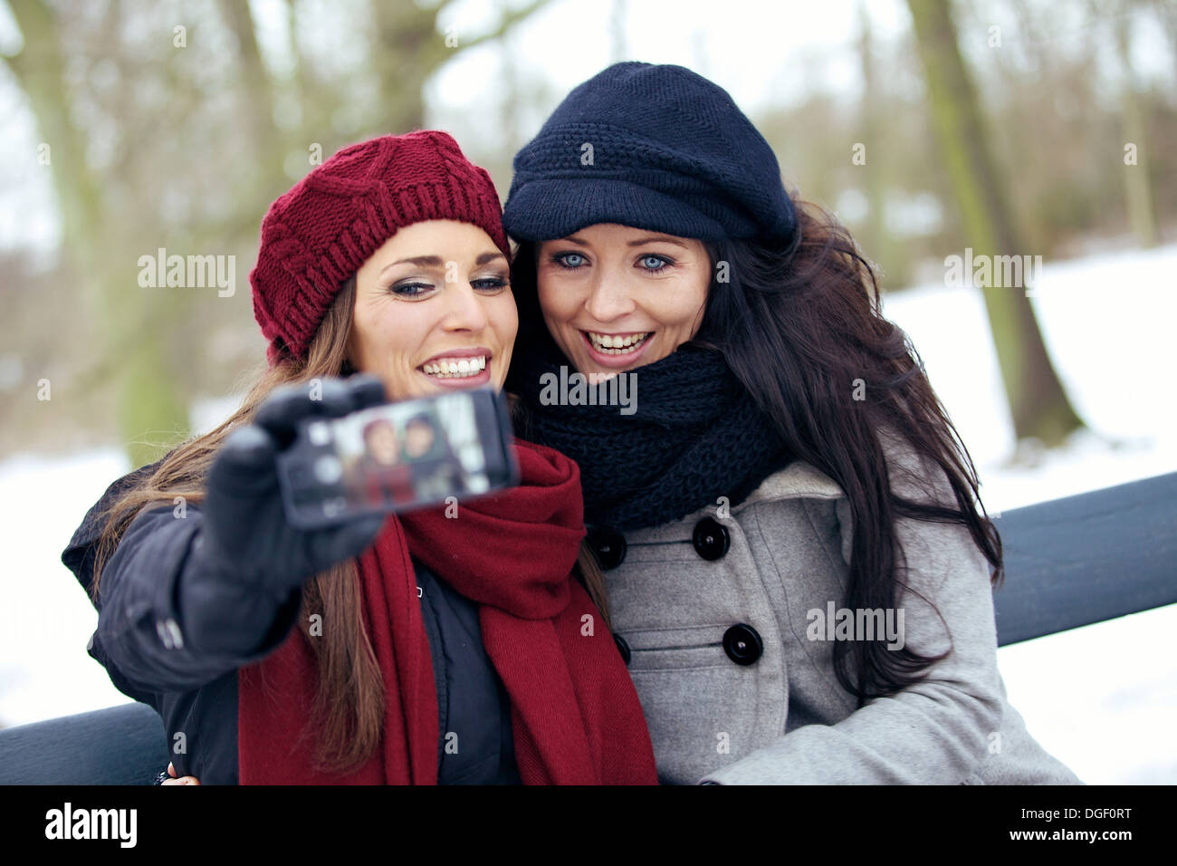 Two beautiful women enjoying the freezing park and taking pictures Stock Photo