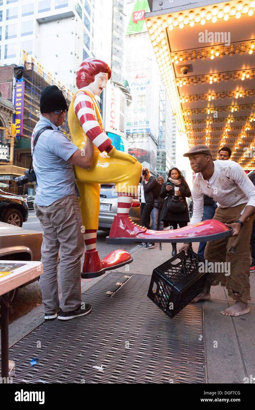 New York, NY, USA. 20th Oct, 2013. A helper and the actor depicting a 'shoe shine boy' remove the mock Ronald McDonald in front of McDonalds in Times Square. The statue was part of a performance art piece put on by British graffiti artist Banksy in Manhattan, New York, as part of his 'Better Out Than in' NY Exhibition. Credit:  Dan Herrick/ZUMAPRESS.com/Alamy Live News Stock Photo