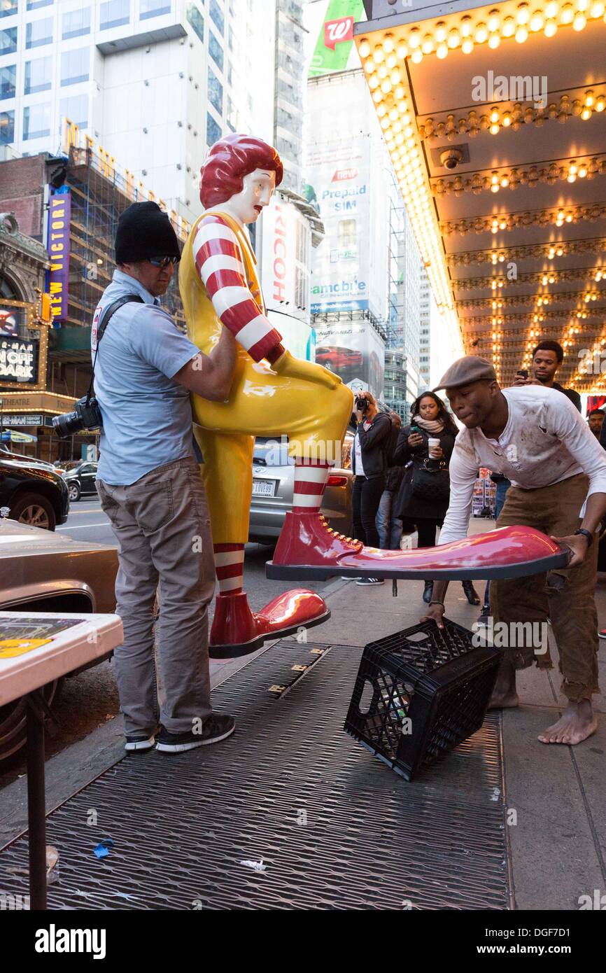 New York, NY, USA. 20th Oct, 2013. A helper and the actor depicting a 'shoe shine boy' remove the mock Ronald McDonald in front of McDonalds in Times Square. The statue was part of a performance art piece put on by British graffiti artist Banksy in Manhattan, New York, as part of his 'Better Out Than in' NY Exhibition. Credit:  Dan Herrick/ZUMAPRESS.com/Alamy Live News Stock Photo