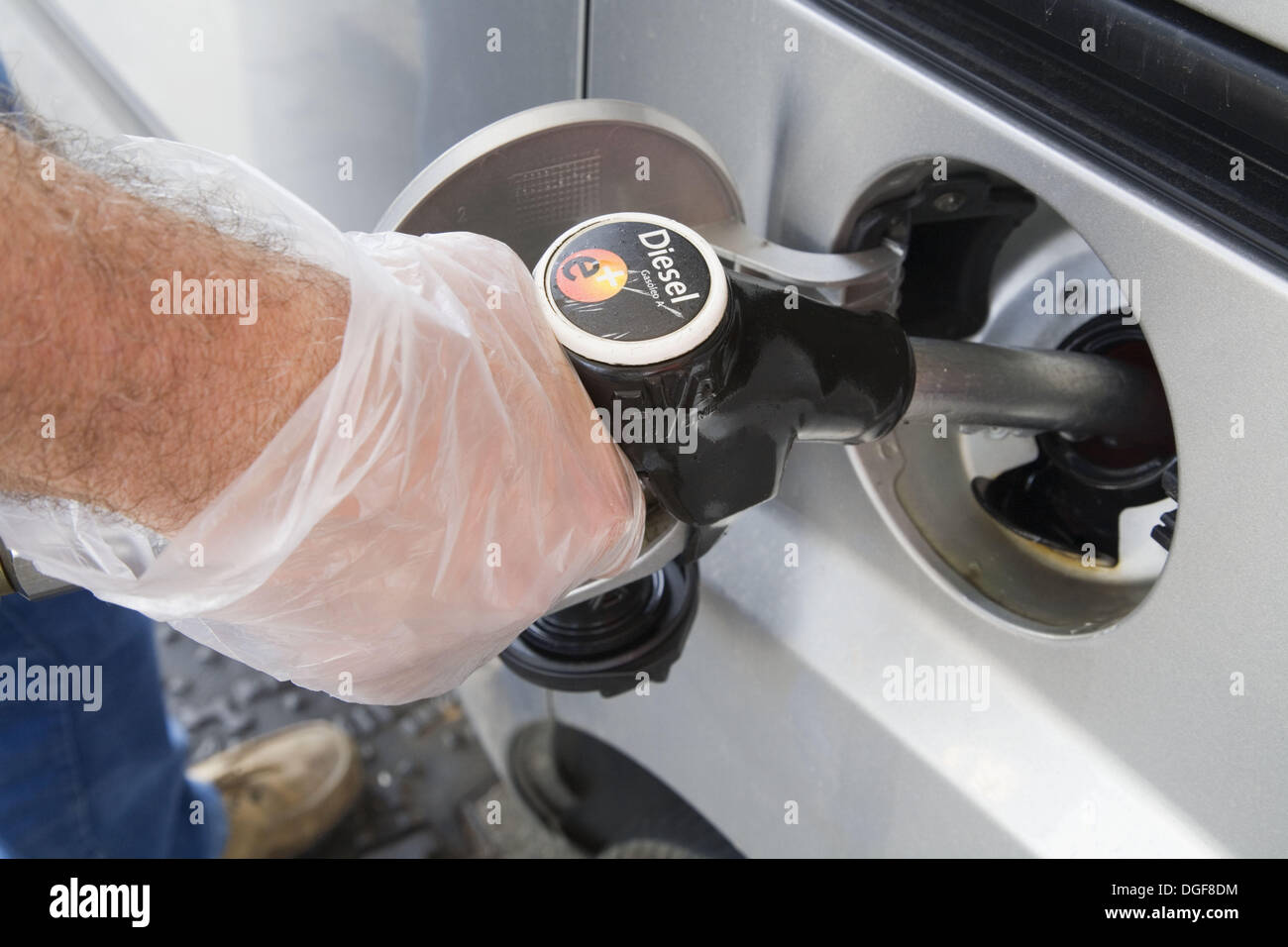 Gloved hand holding gas pump nozzle in car fuel tank Stock Photo Alamy