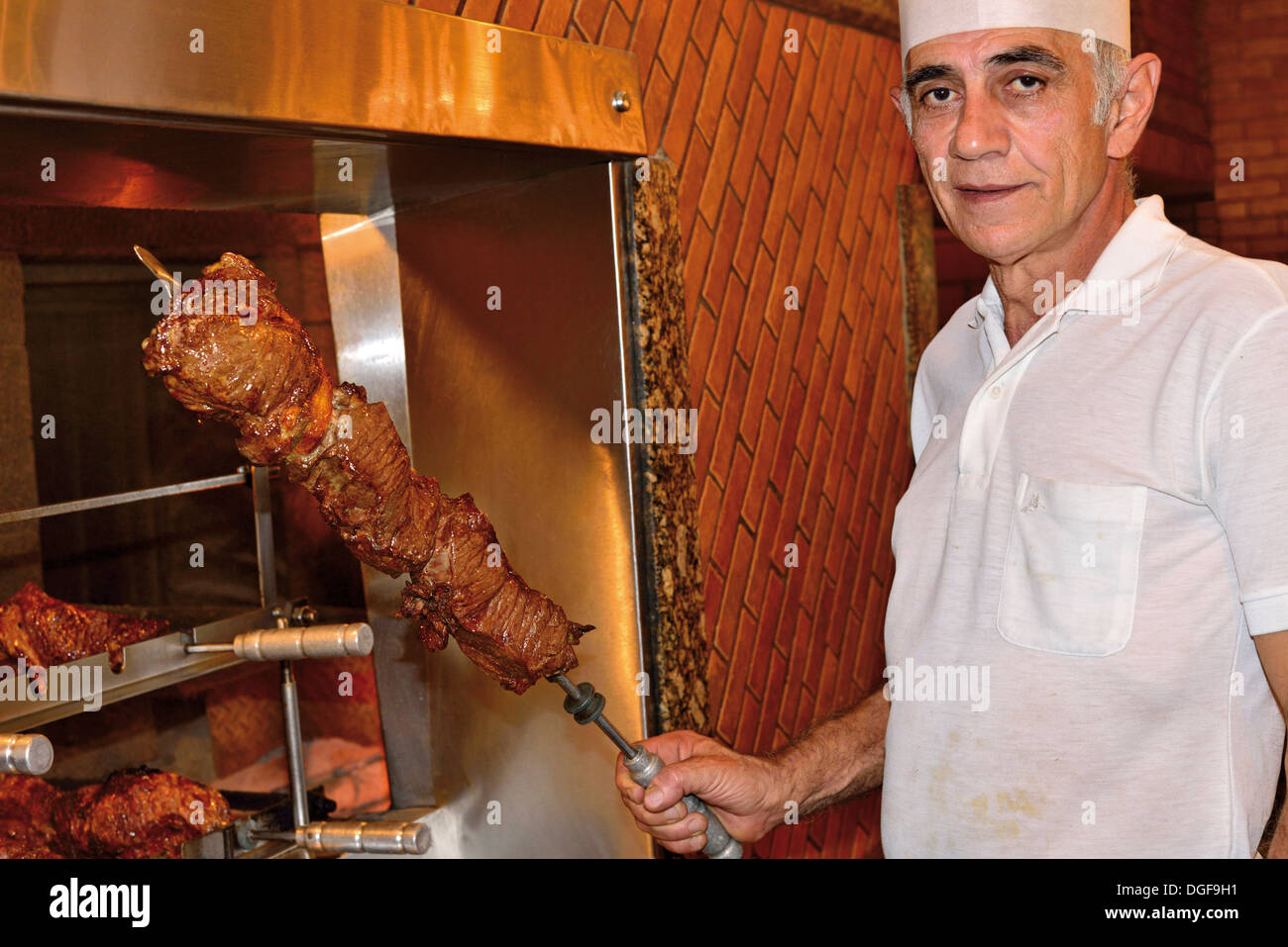 Brazil, Foz do Iguacu: Mr. Afonso showing huge skewer with meat in the grill restaurant Churrascaria Rafain Stock Photo