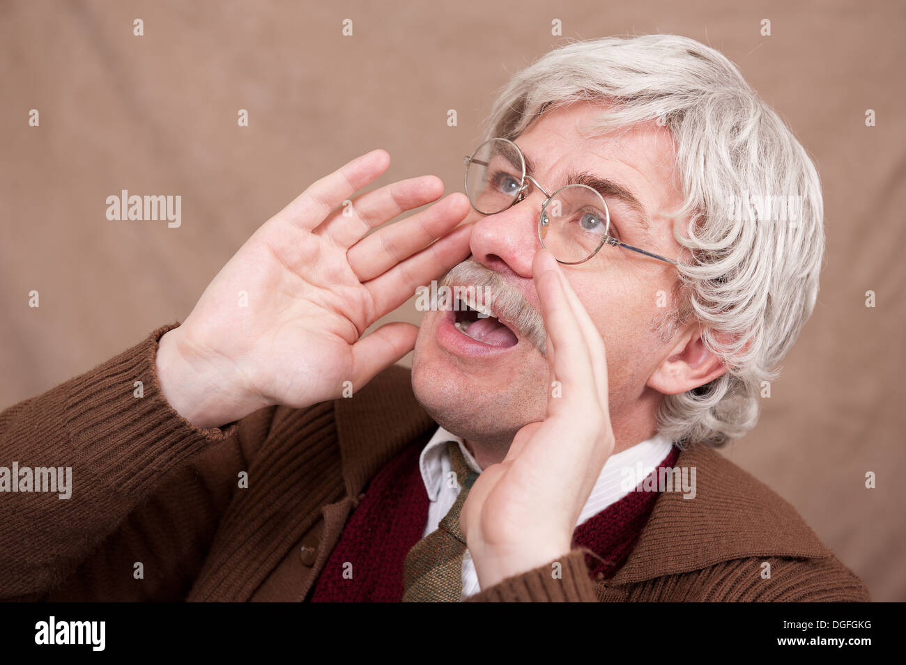 Grey haired old man using his hands to shout louder. Stock Photo