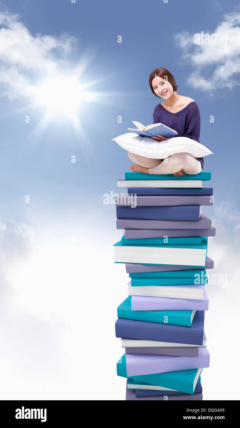 a woman sitting on a pile of books Stock Photo - Alamy