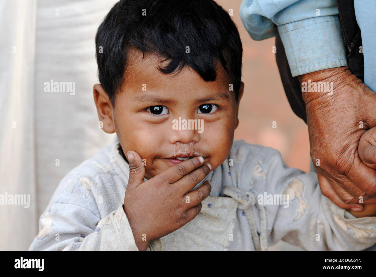 Young boy holding adult's hand, Taumadhi square, Bhaktapur, Kathmandu