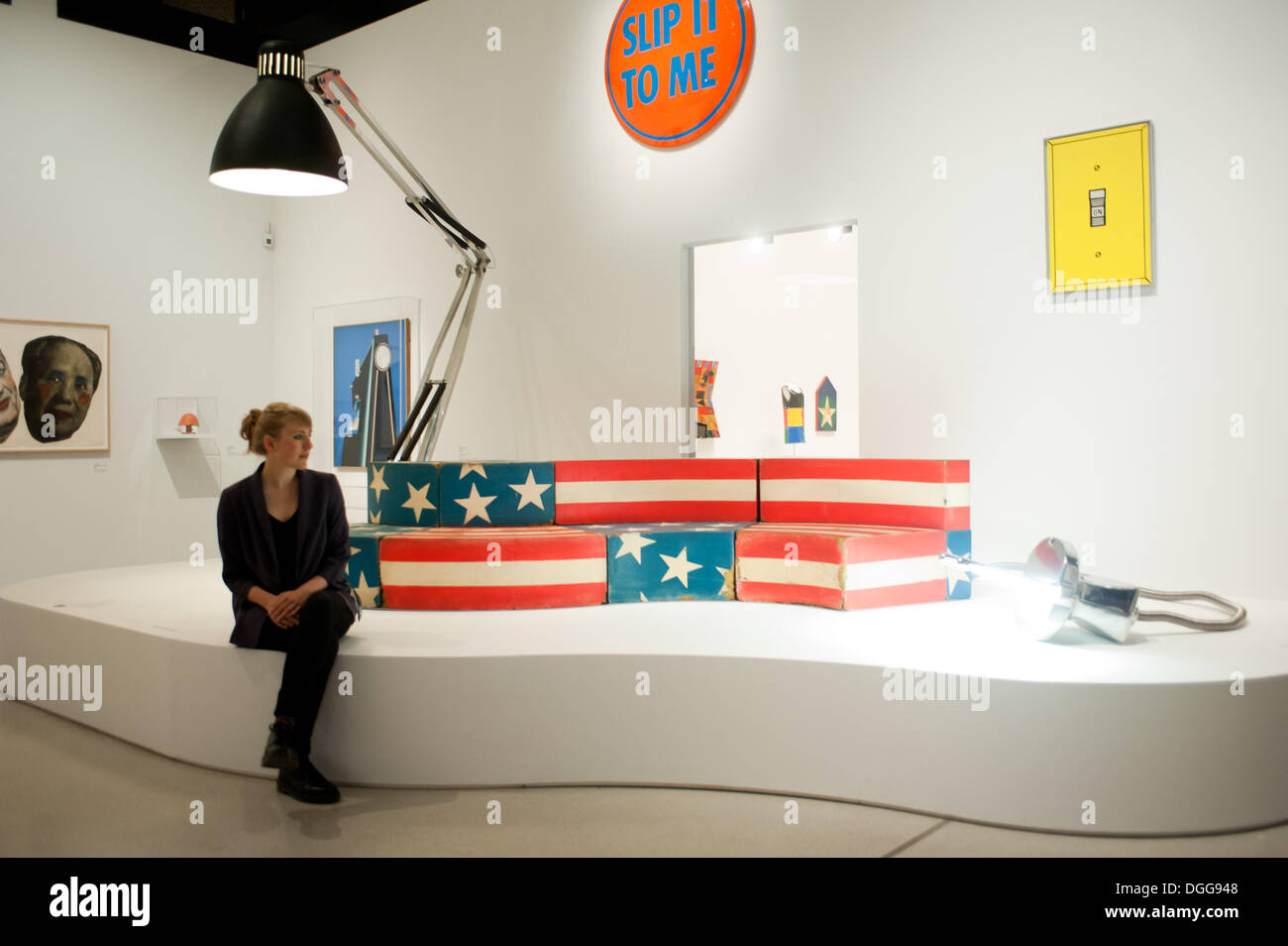 London, UK - 21 October 2013: a woman sits next to woks of art including 'Moloch, floor lamp, 1970-71' by Gaetano Pesce (L) and 'Leonardo, Sofa, 1969' by Studio 65 (C)  during the Pop Art Design exhibition at Barbican gallery in London. Credit:  Piero Cruciatti/Alamy Live News Stock Photo