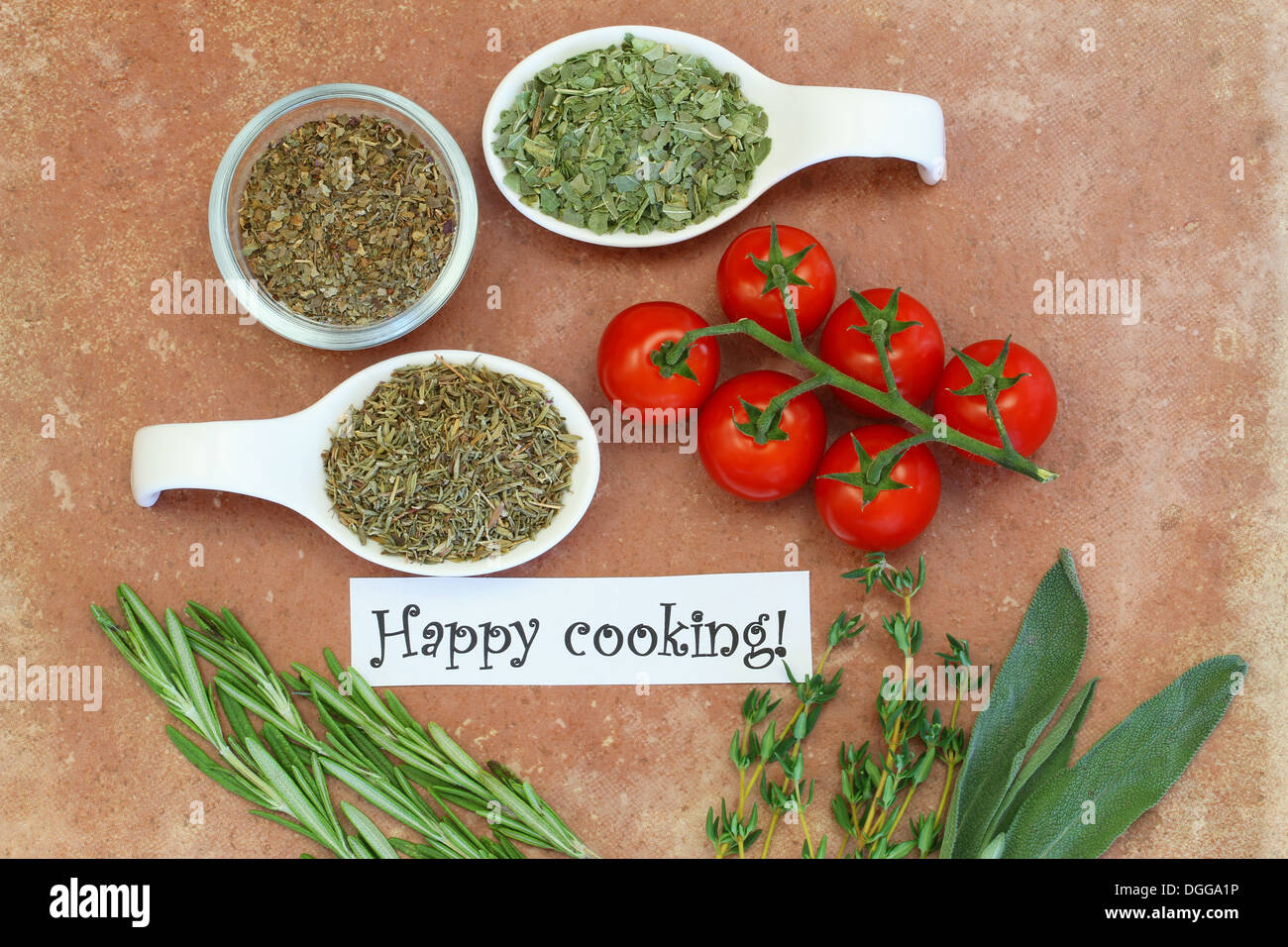 Happy cooking card with cherry tomatoes, fresh and dried herbs on terracotta surface Stock Photo