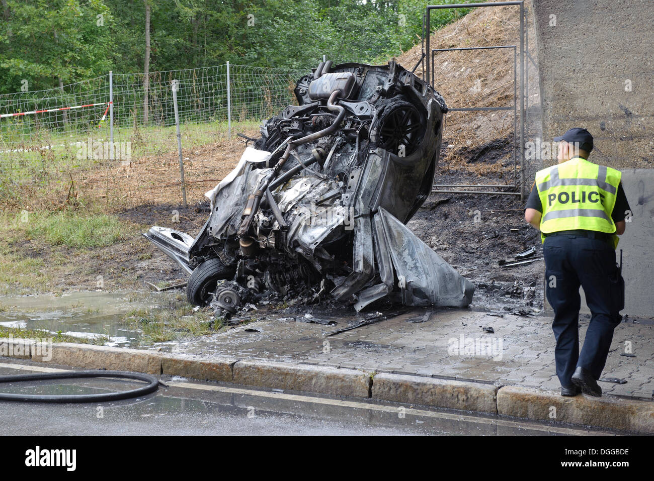Wreck of an Audi car after a violent collision against the pillar of a bridge, US military police officer attending the wreckage Stock Photo