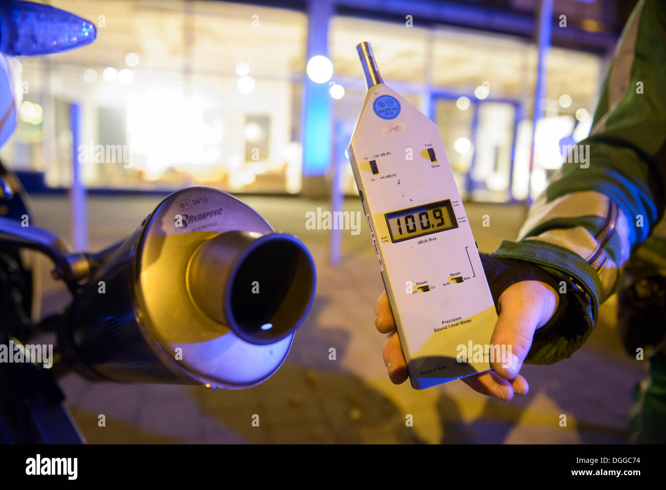 Police control, policeman holding a noise level meter beside the exhaust of a motorcycle whose noise reduction device has been Stock Photo