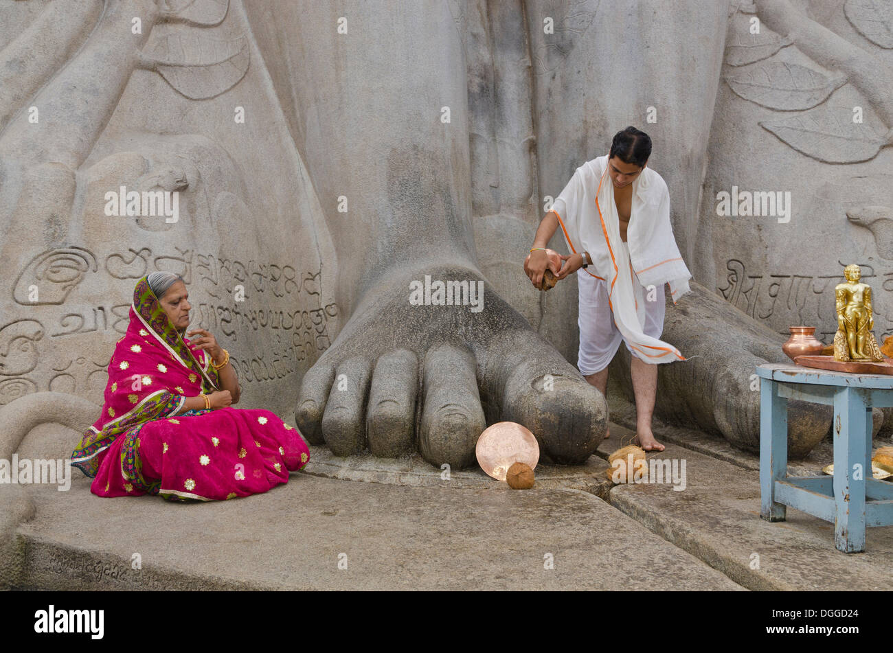 Priest is pouring water on the feet of the gigantic statue of Gomateshwara in Sravanabelagola, pilgrim meditating Stock Photo