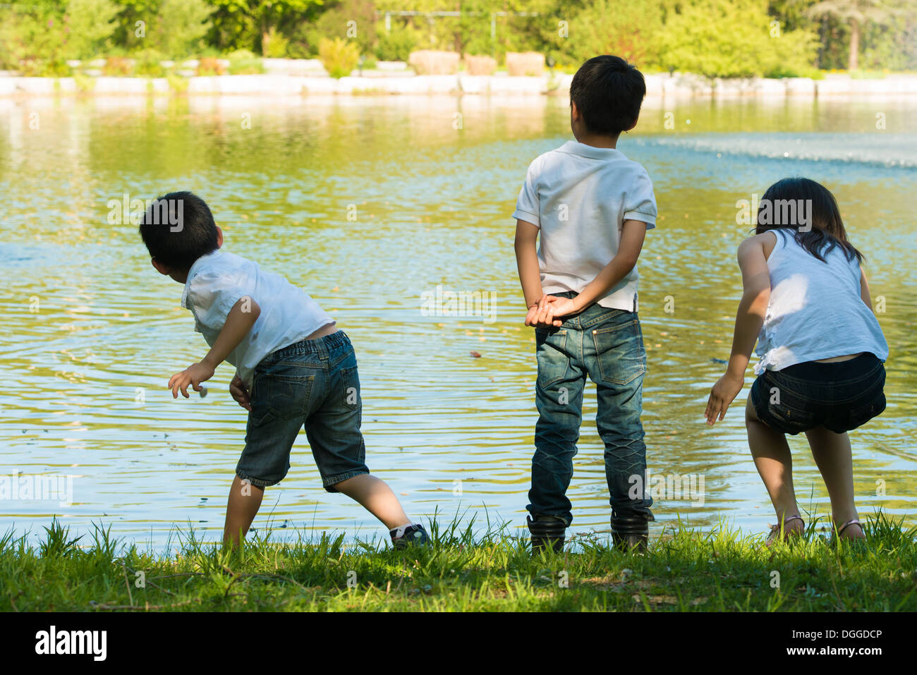 Three children playing by lake Stock Photo