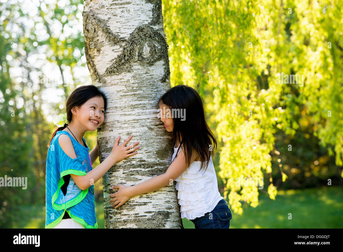 Two girls hugging tree Stock Photo