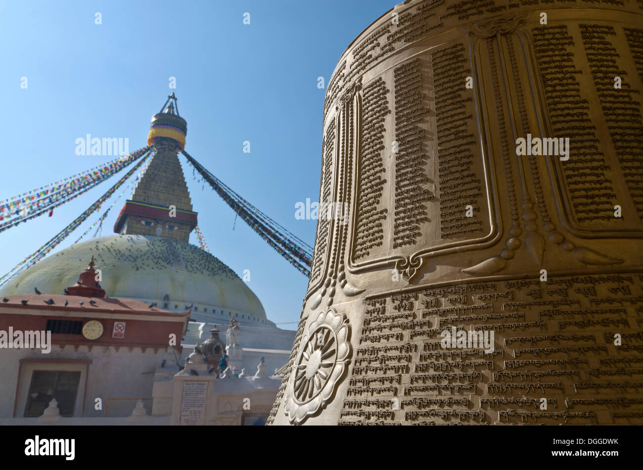 Big bell with Tibetan inscription, Boudnath Stupa at back, Kathmandu Valley, Kathmandu, Kathmandu District, Bagmati Zone, Nepal Stock Photo