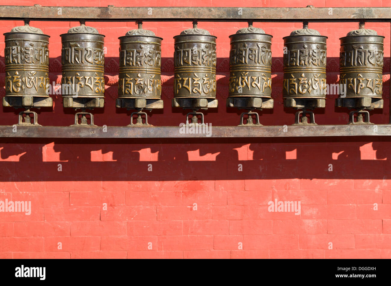 Buddhist prayer wheels in front of a red wall at Swayambhunath Stupa ...