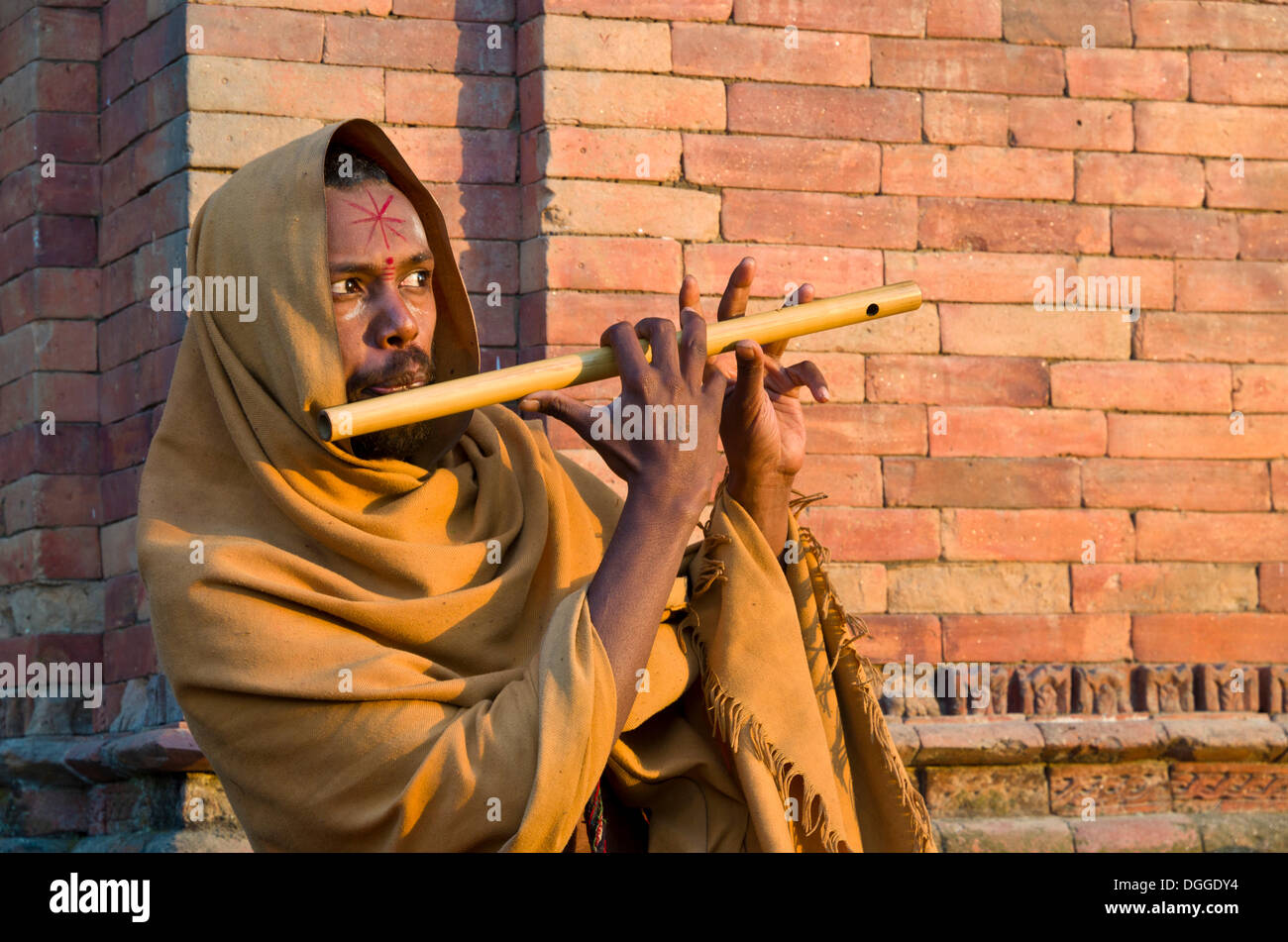 Young man playing flute at the burning ghats, Kathmandu, Kathmandu District, Bagmati Zone, Nepal Stock Photo