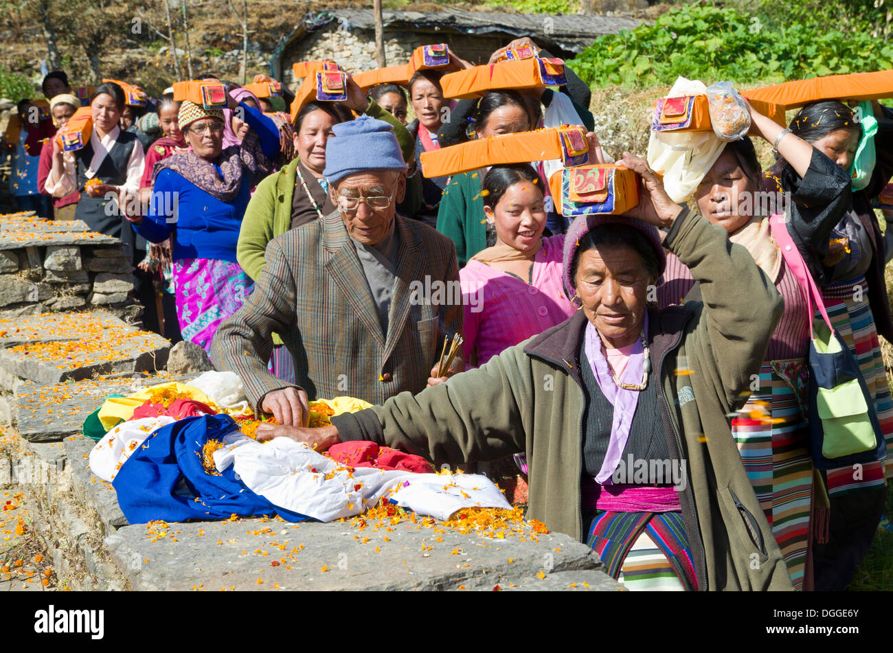 People carrying tibetean prayer books, wrapped in yellow material, on their heads at Lhapab Tuchen festival, Bhandar Stock Photo