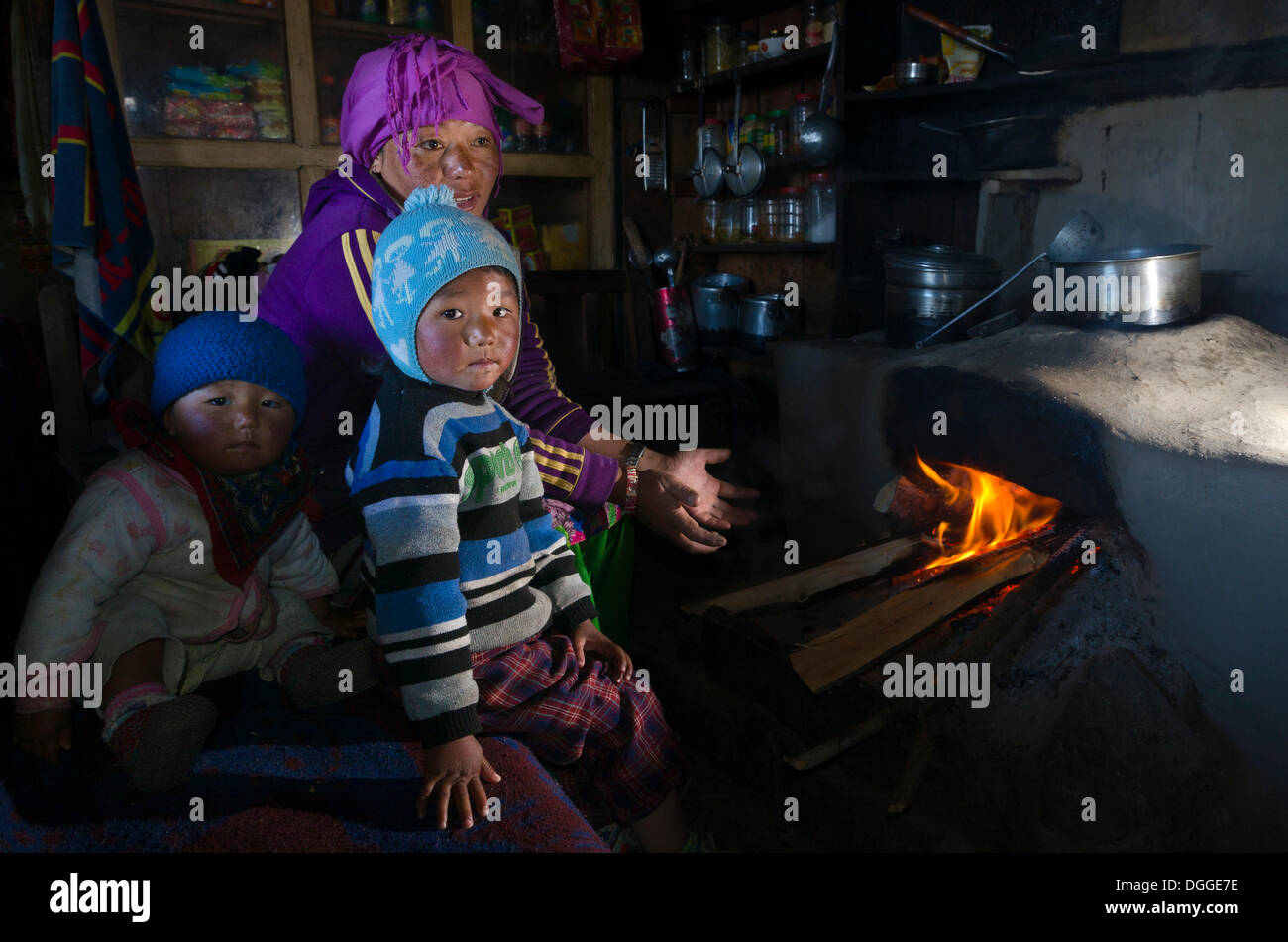 Nepali mother with her 2 children sitting at the fireplace in their kitchen, Goyam, Solukhumbu District, Sagarmāthā Zone Stock Photo