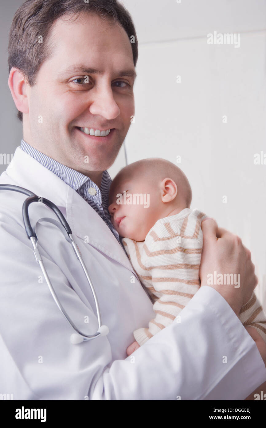 Mid adult doctor holding baby boy, portrait Stock Photo