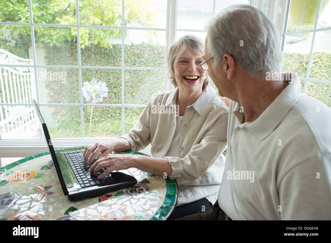 Senior couple using laptop in conservatory Stock Photo
