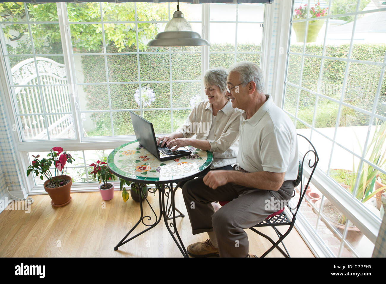 Senior couple using laptop in conservatory Stock Photo