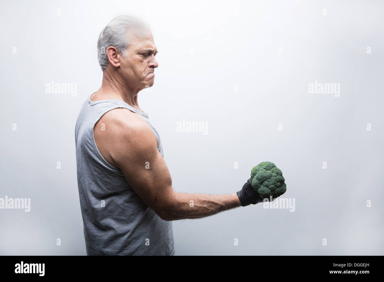 Senior man in sports clothing lifting broccoli Stock Photo