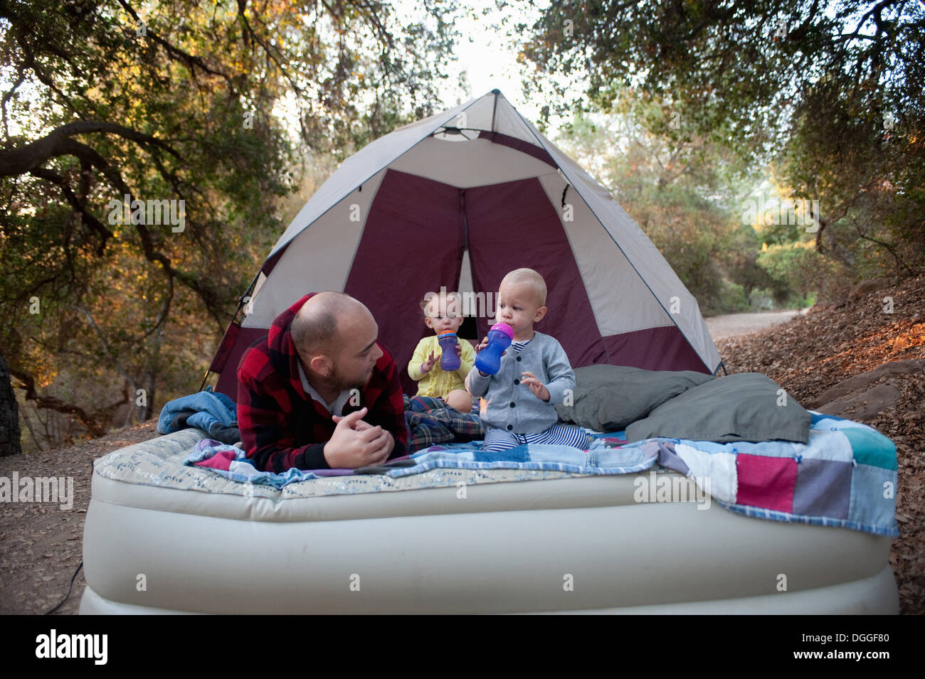 Toddler twins on camping mattress with father Stock Photo Alamy
