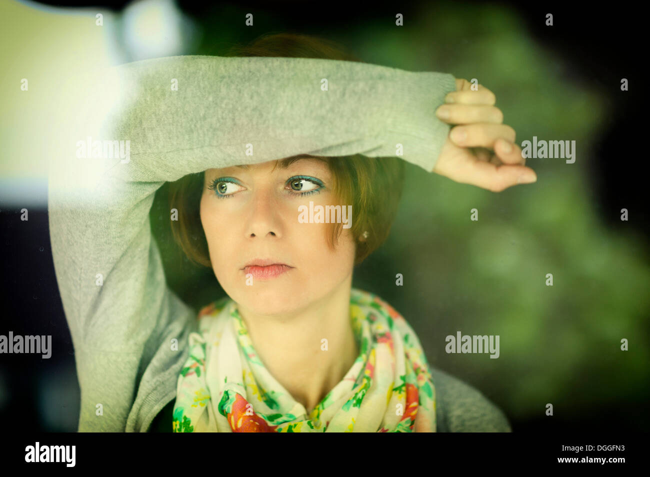 Young pensive woman looking through a window, Grevenbroich, Rhineland, North Rhine-Westphalia, Germany Stock Photo
