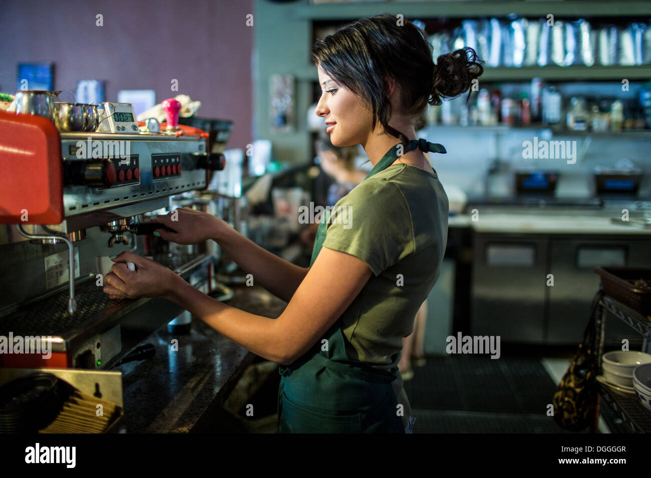 Teenage waitress preparing coffee in cafe kitchen Stock Photo