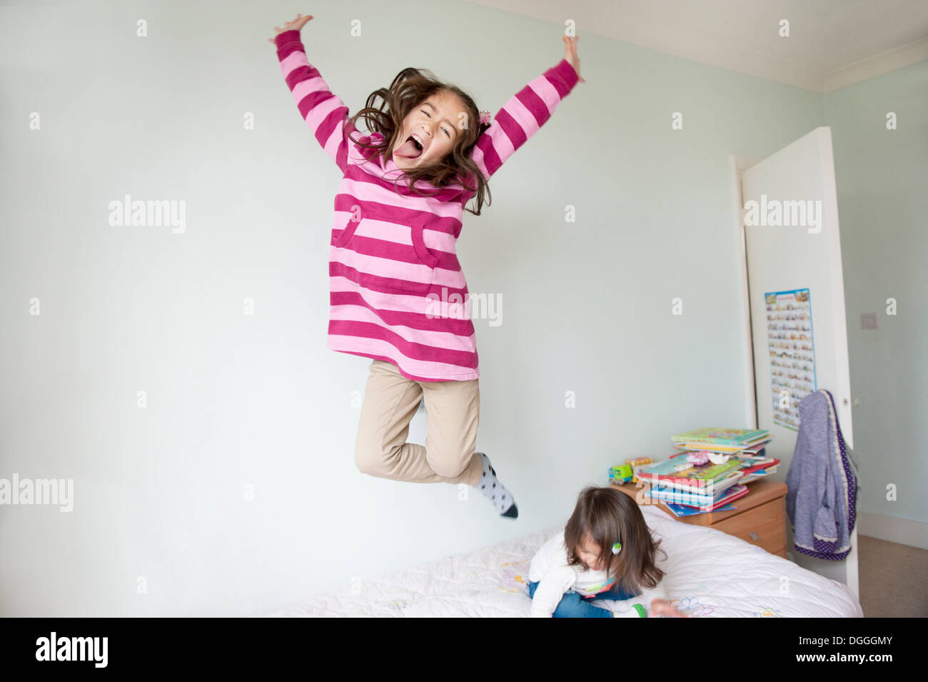 Girl jumping on bed and pulling face Stock Photo