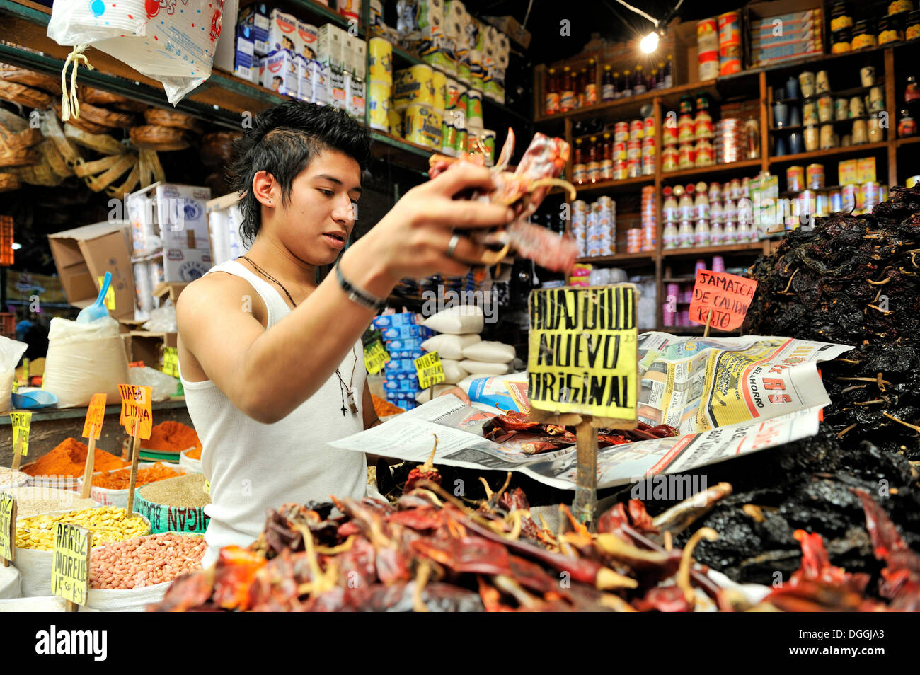 Youth selling spices and other ingredients in his market stall, packaging of chili peppers, urban markets of Puebla, Mexico Stock Photo