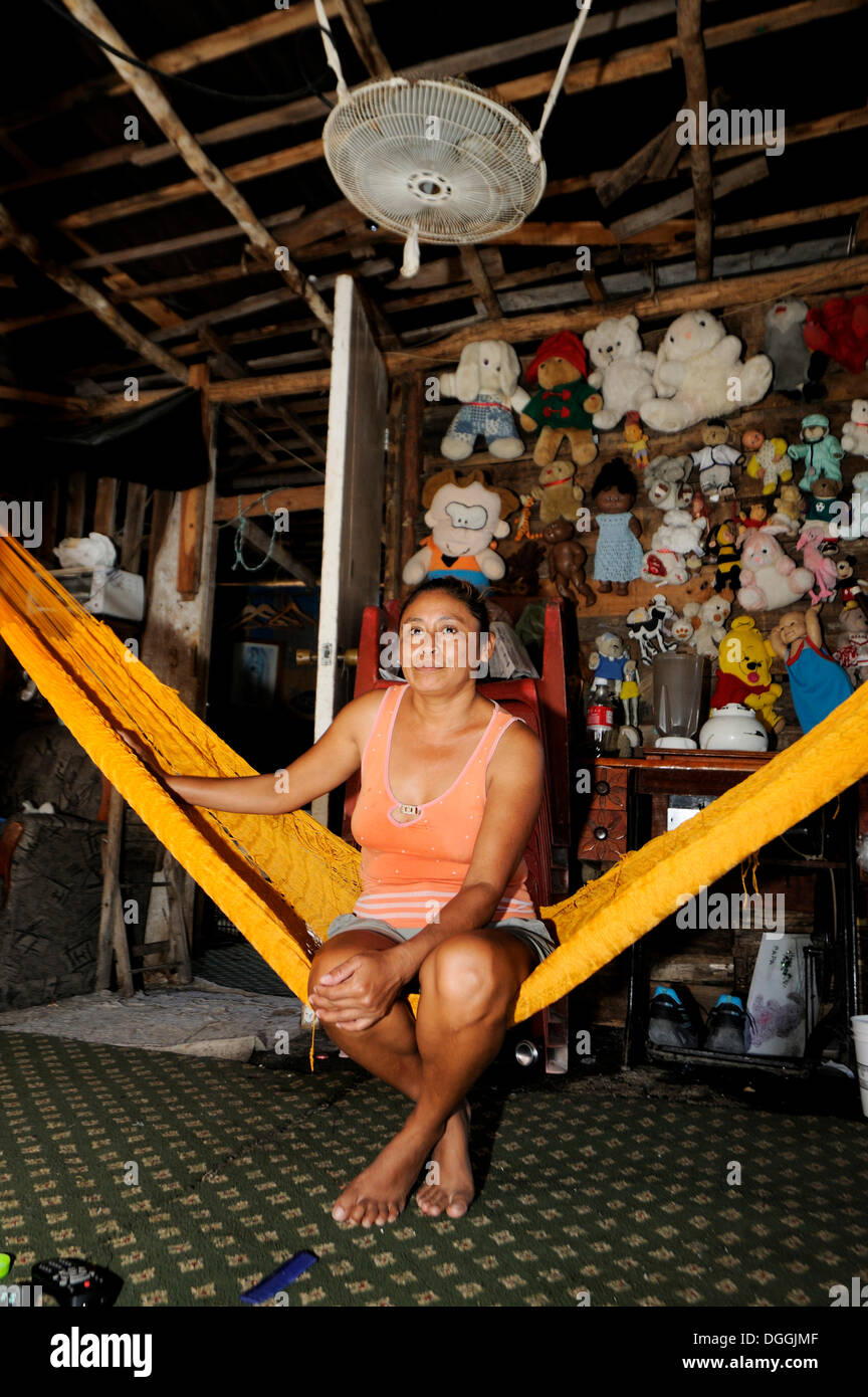 Woman sitting on a hammock in a simple wooden hut, in a poor neighborhood of Cancun, Yucatan Peninsula, Quintana Roo, Mexico Stock Photo