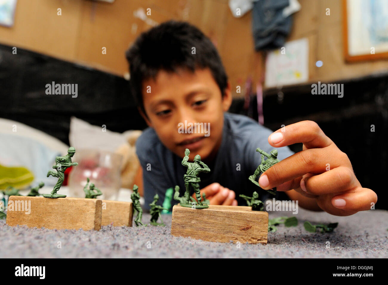 Boy playing with plastic toy soldiers, in a poor district of Cancun, Yucatan Peninsula, Quintana Roo, Mexico, Latin America Stock Photo