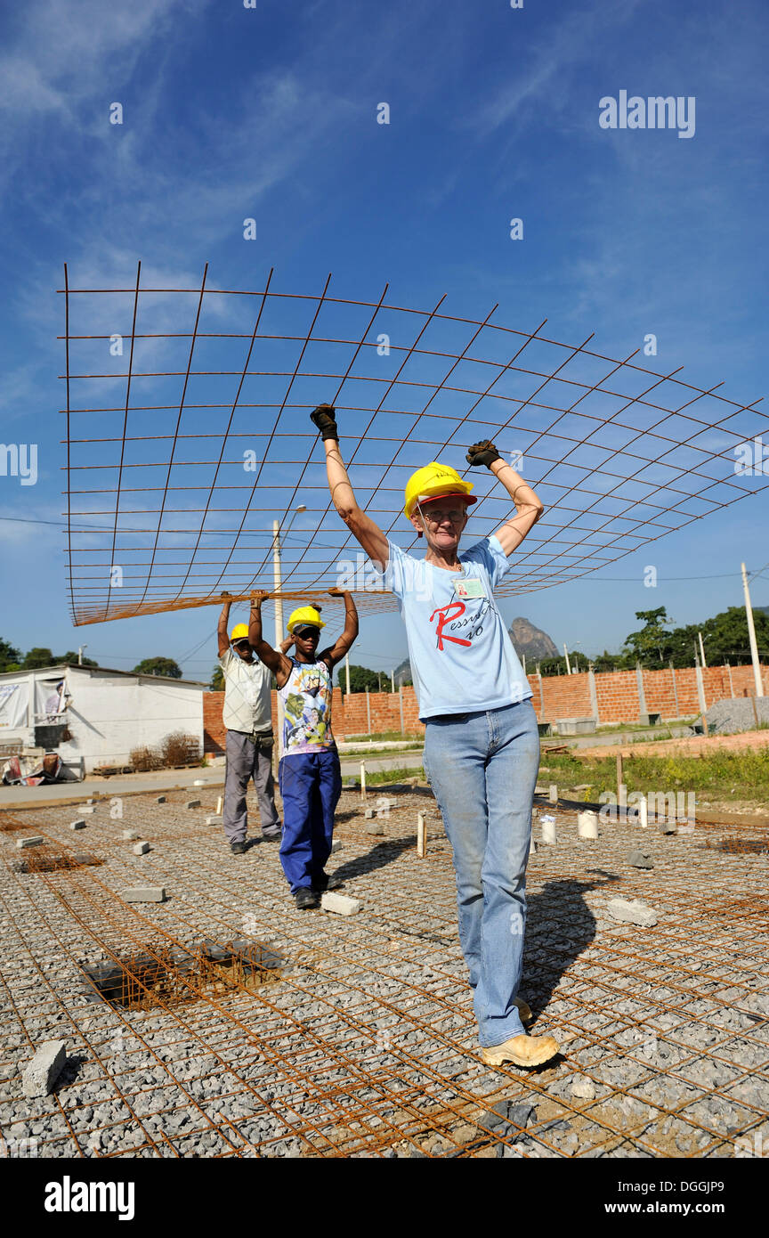 Woman and men carrying construction steel, people from the poor neighbourhood working together on a building site of the Stock Photo