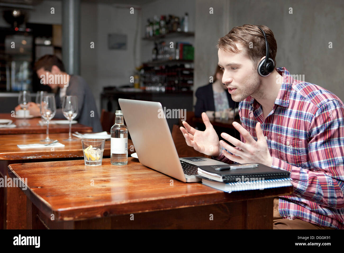 Young man wearing headphones using laptop in cafe Stock Photo
