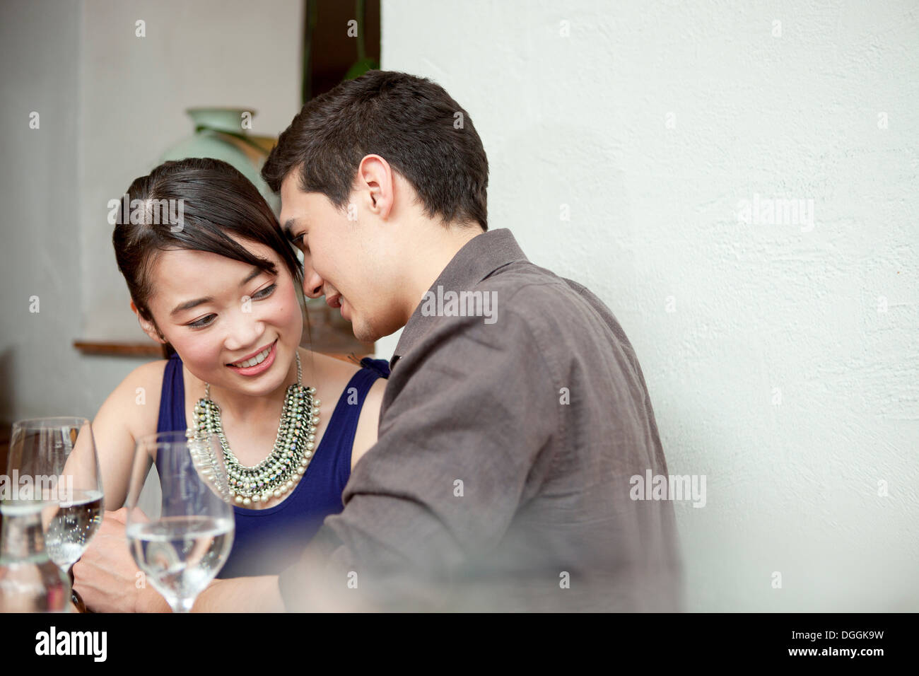 Young couple in restaurant, man whispering Stock Photo
