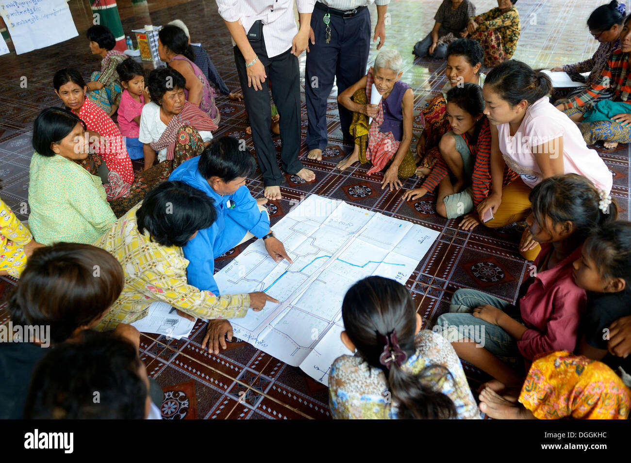 Men and women from the village discussing with representatives of a charity organization, over a map in which the springs and Stock Photo