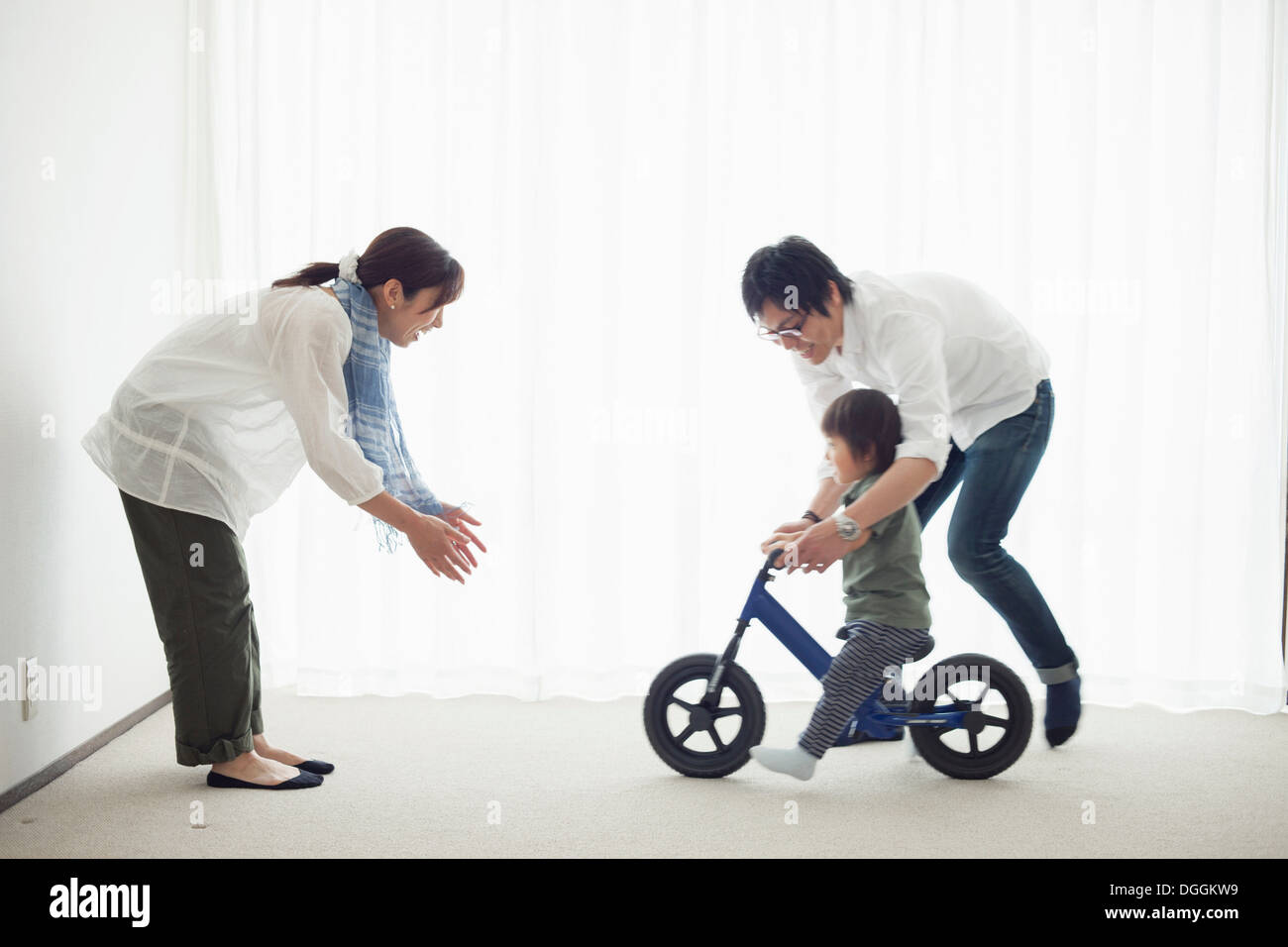 Parents with son learning to ride bicycle Stock Photo