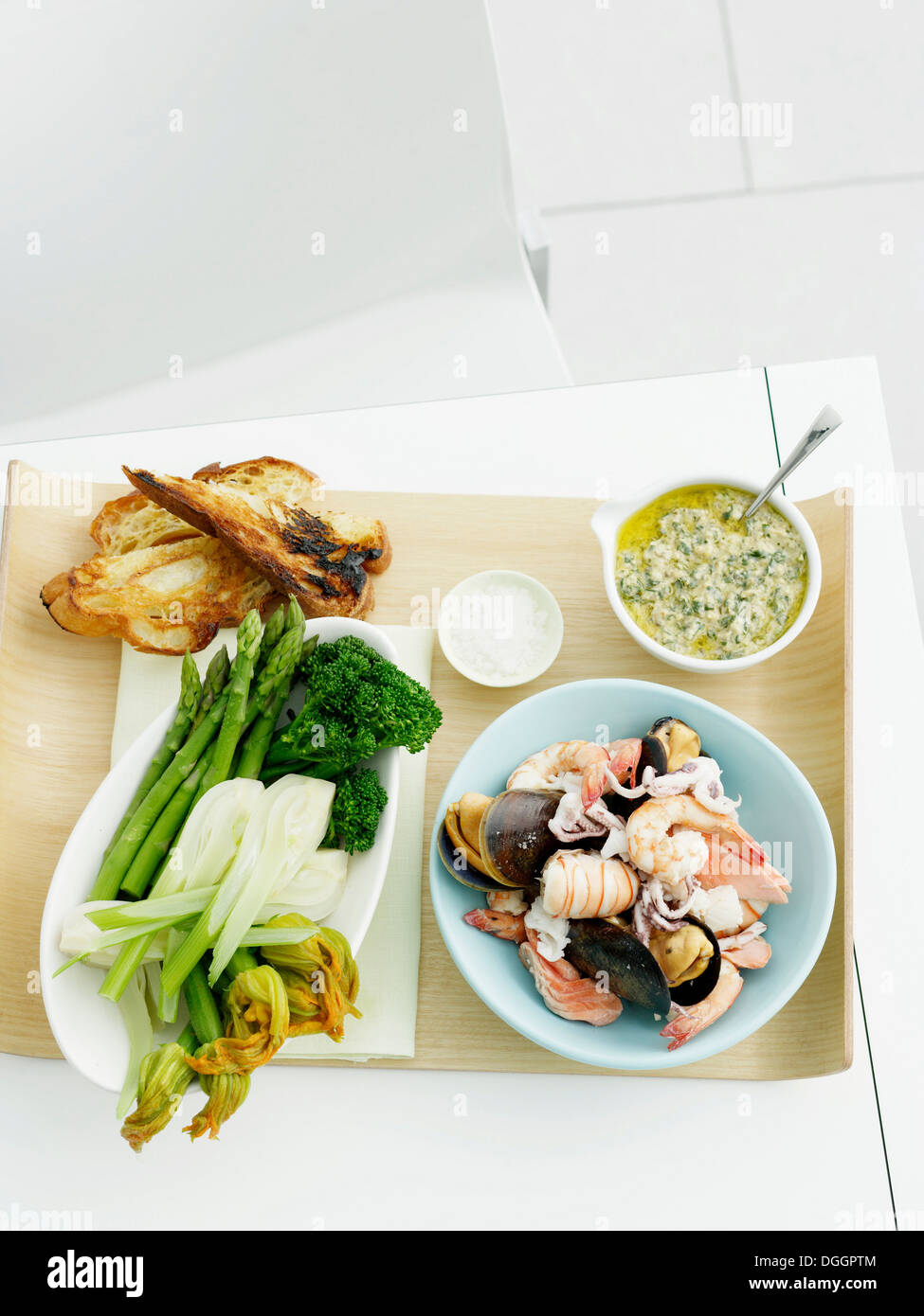Salsa verde, mixed seafood, fennel, zucchini, asparagus, broccolini and bread Stock Photo