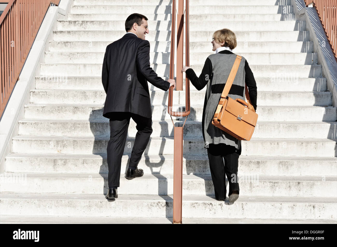 Businesswoman and man ascending staircase, outdoors Stock Photo