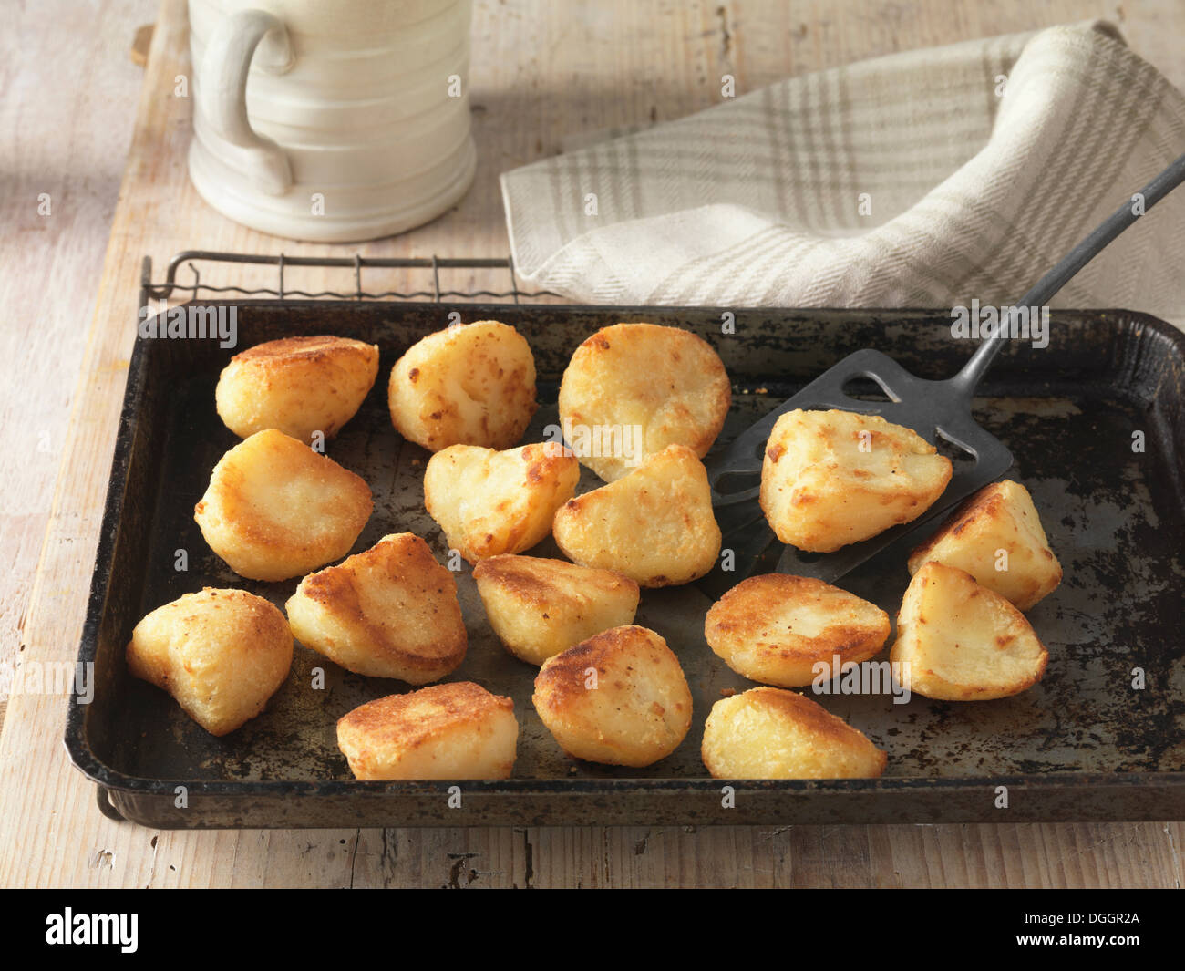 Beef dripping roast potatoes on baking tray and wire rack Stock Photo